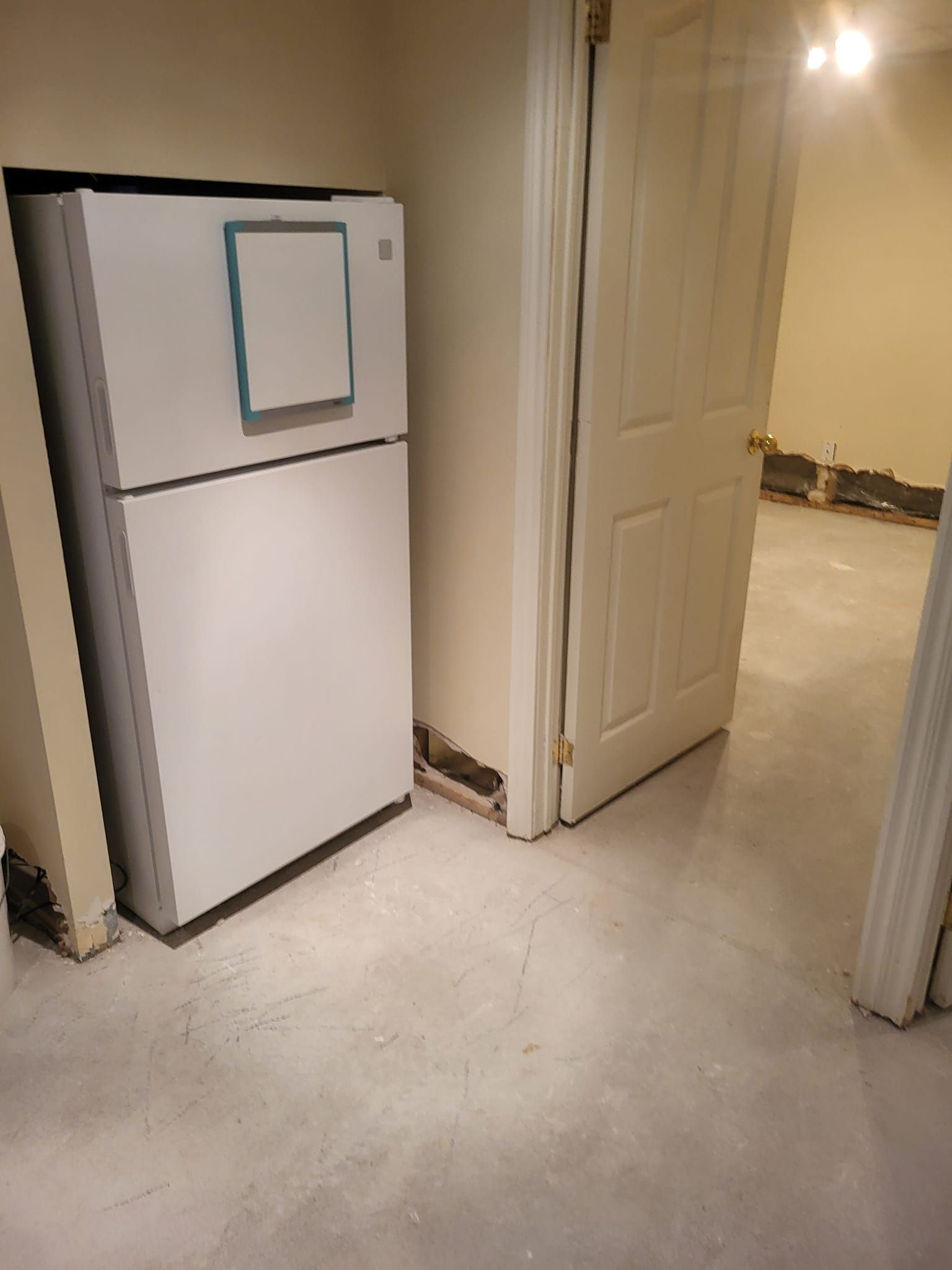 Un réfrigérateur blanc se trouve dans une pièce à côté d'une porte.