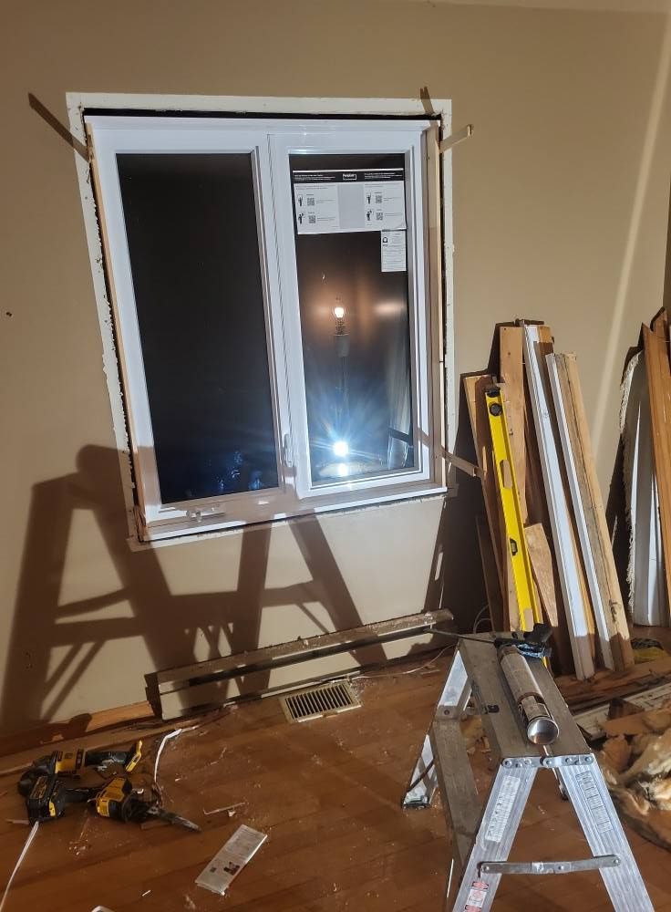 Une fenêtre est en cours d'installation dans une pièce avec une échelle et des outils.