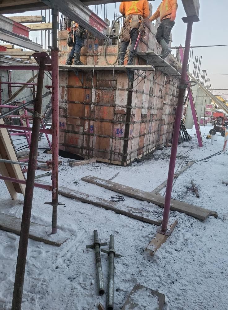 Un groupe d'ouvriers du bâtiment travaille sur un bâtiment sous la neige.