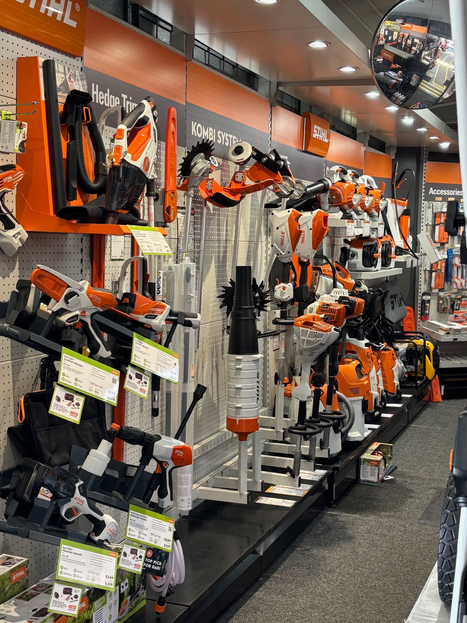 Inside a hardware store, a variety of lawnmowers and power tools are on display for sale.