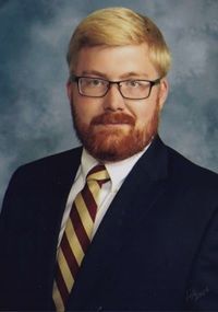 a man with a beard and glasses is wearing a suit and tie .