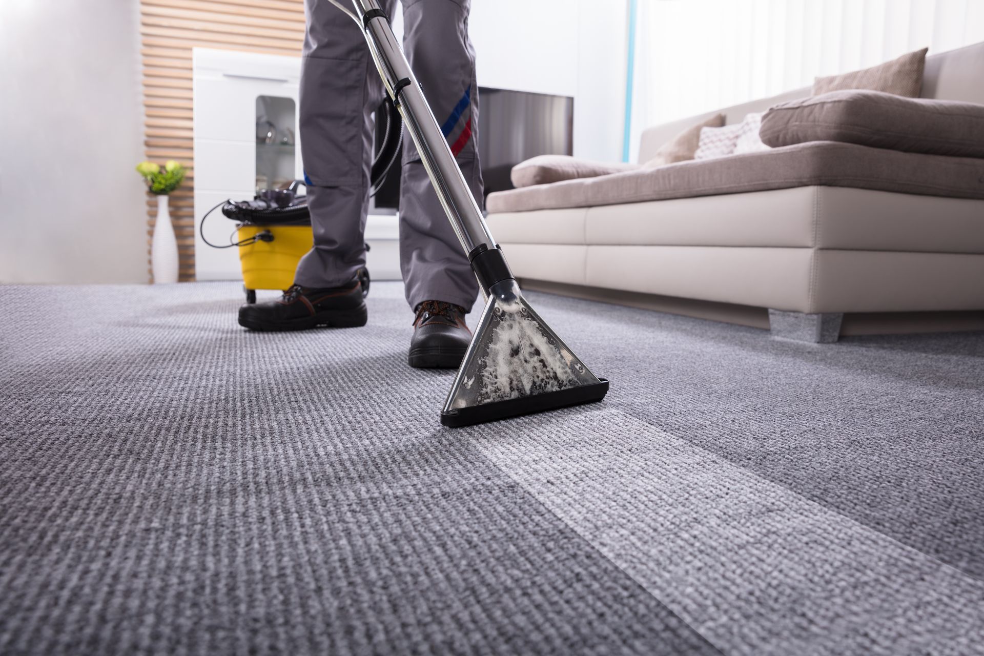 A man is cleaning a carpet with a vacuum cleaner in a living room.