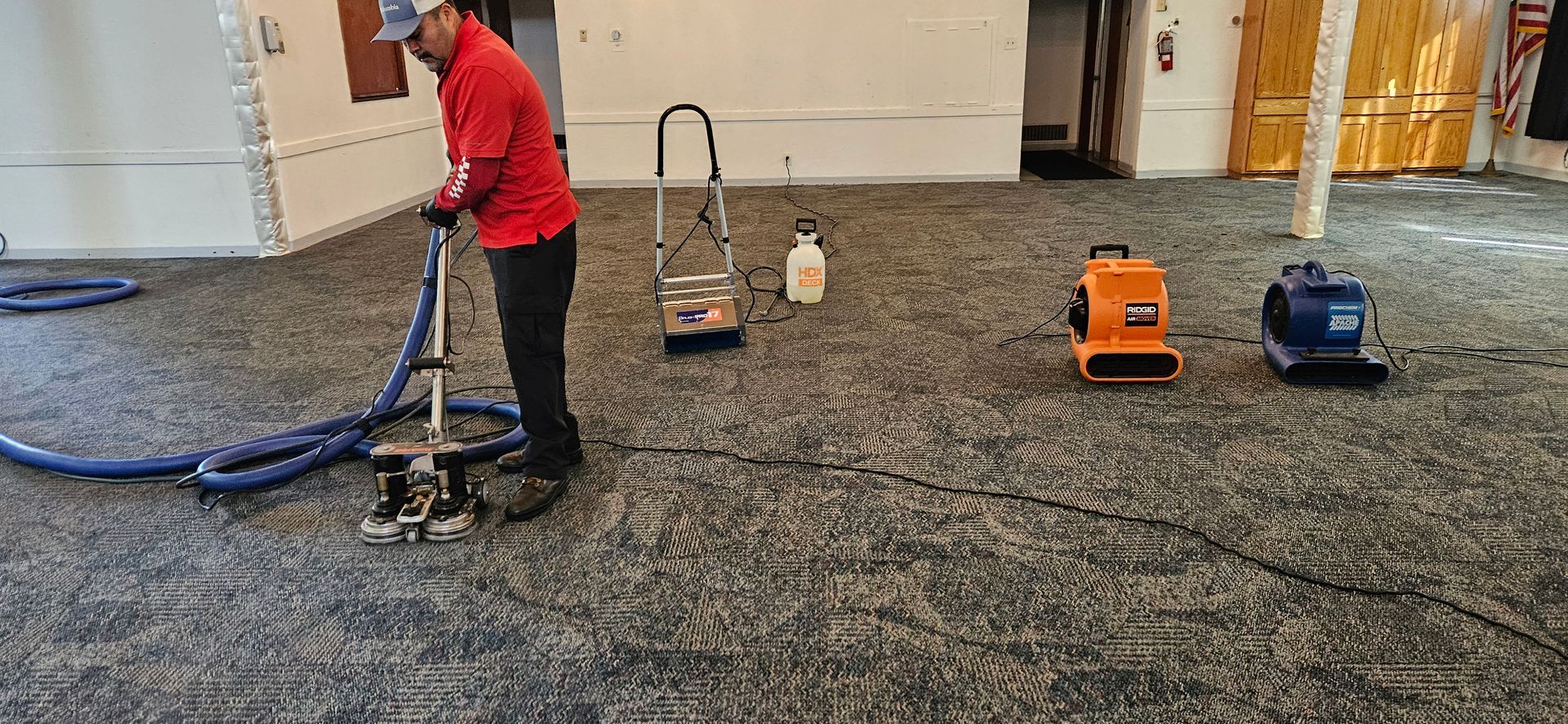 A man is using a vacuum cleaner to clean a carpet in a room.