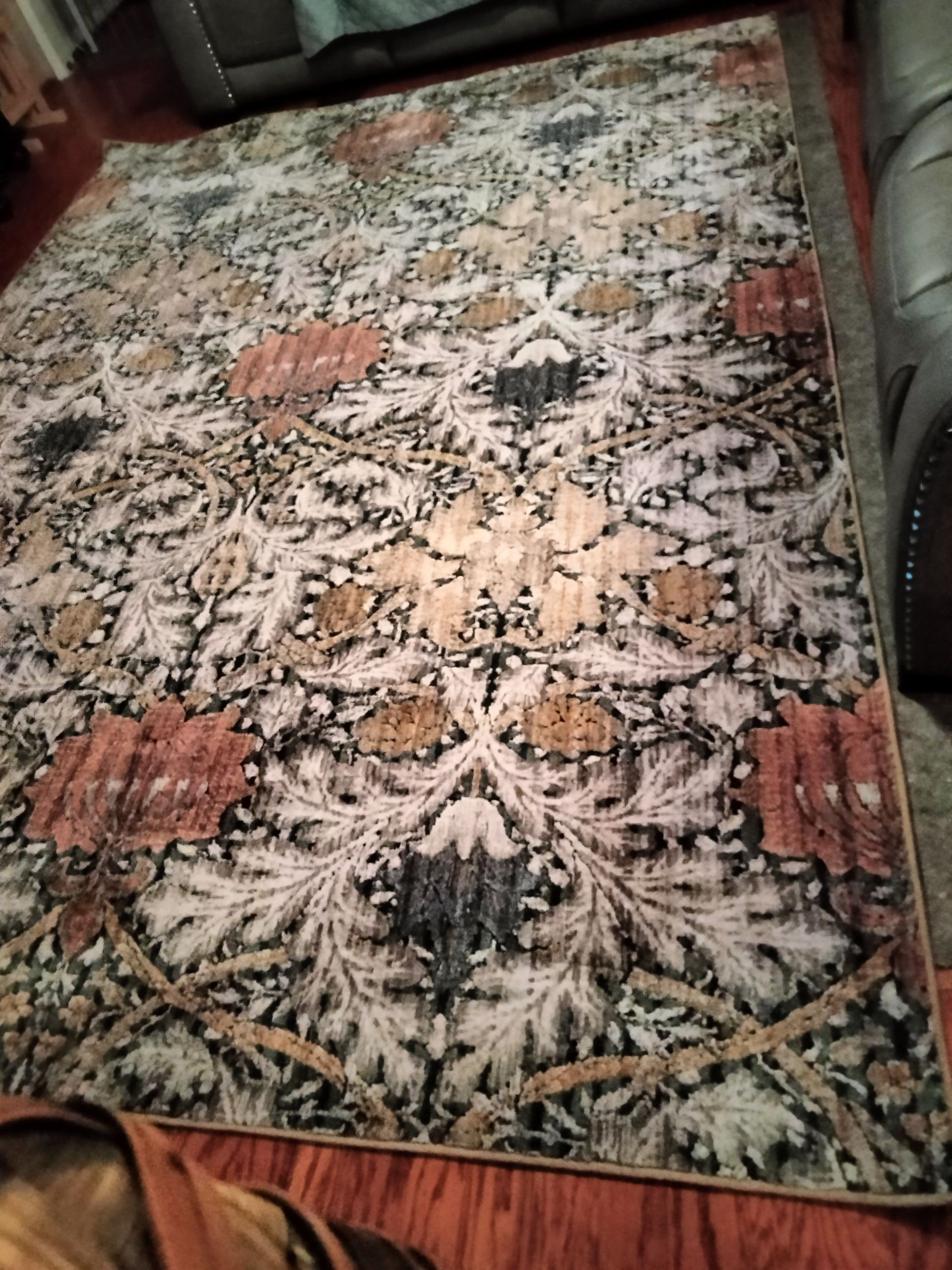 A rug is sitting on a wooden floor in a living room.