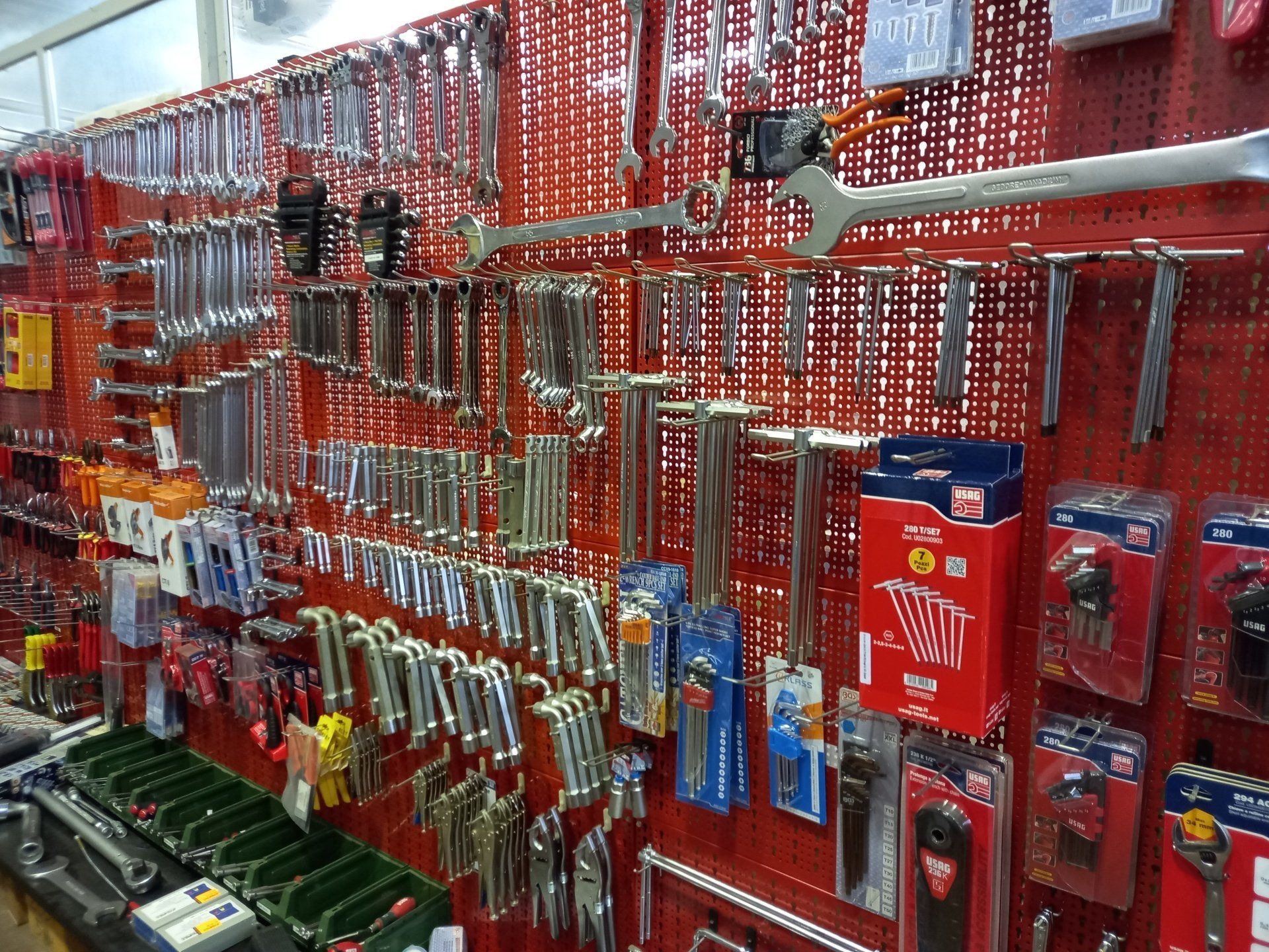 Un mucchio di attrezzi è appeso a una parete rossa in un negozio.