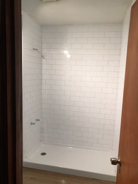 A bathroom with white tiles and a walk in shower.