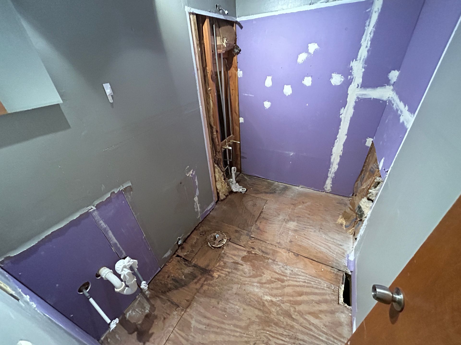 A bathroom under construction with purple walls and a wooden floor.