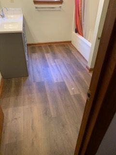 A bathroom with hardwood floors , a sink , and a bathtub.