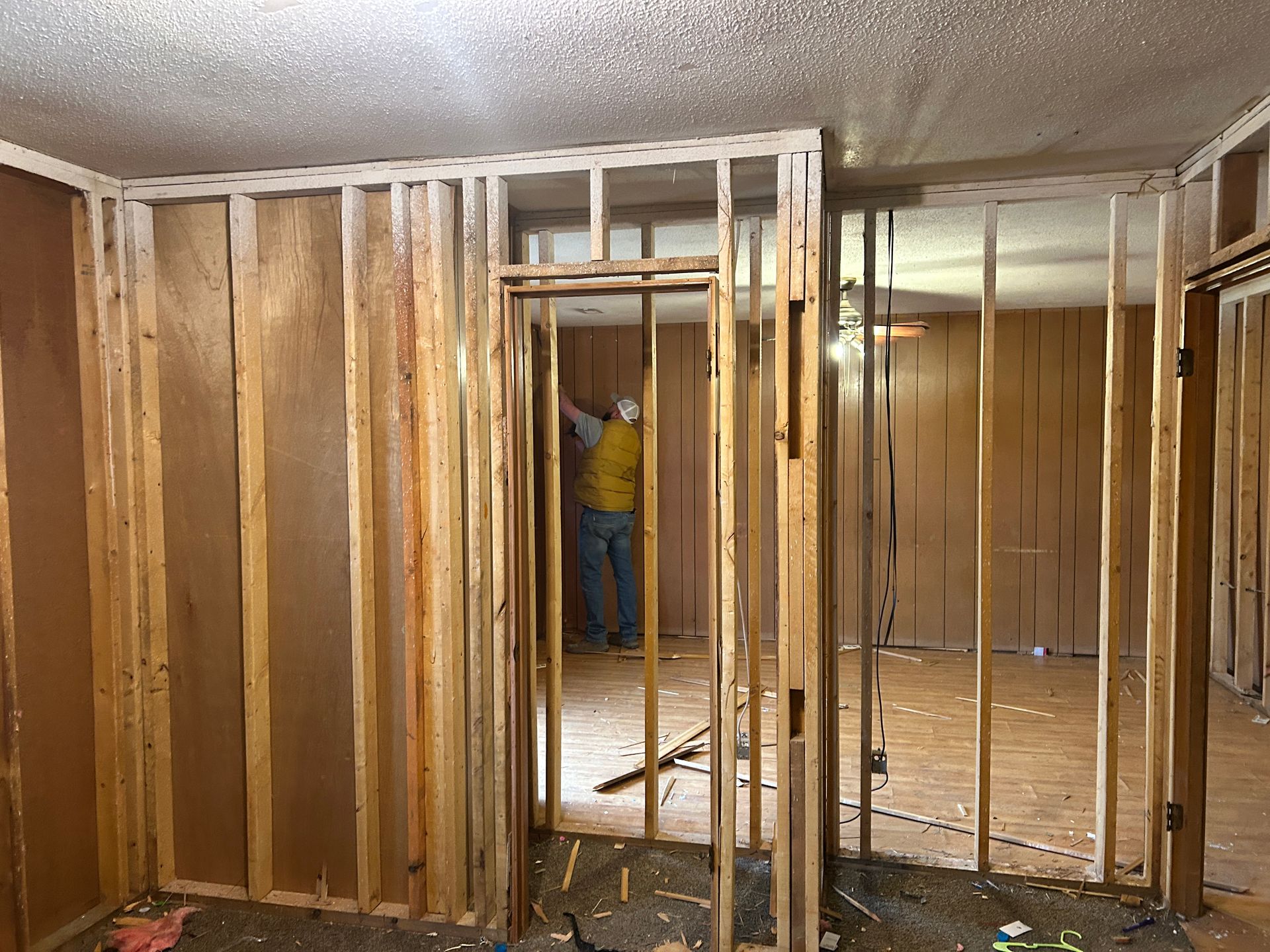 A man is standing in a room with wooden walls.