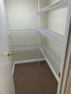 An empty walk in closet with shelves and a door.