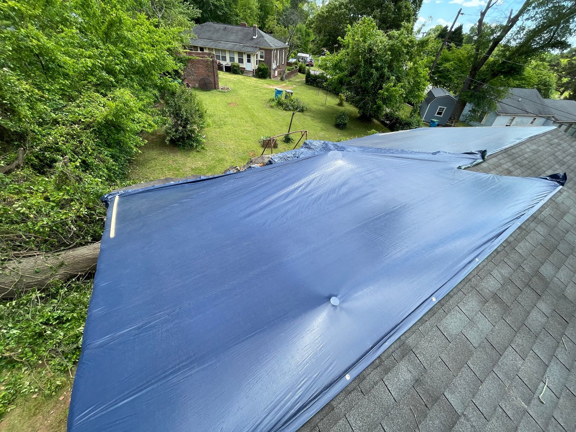 A blue tarp is covering the roof of a house.