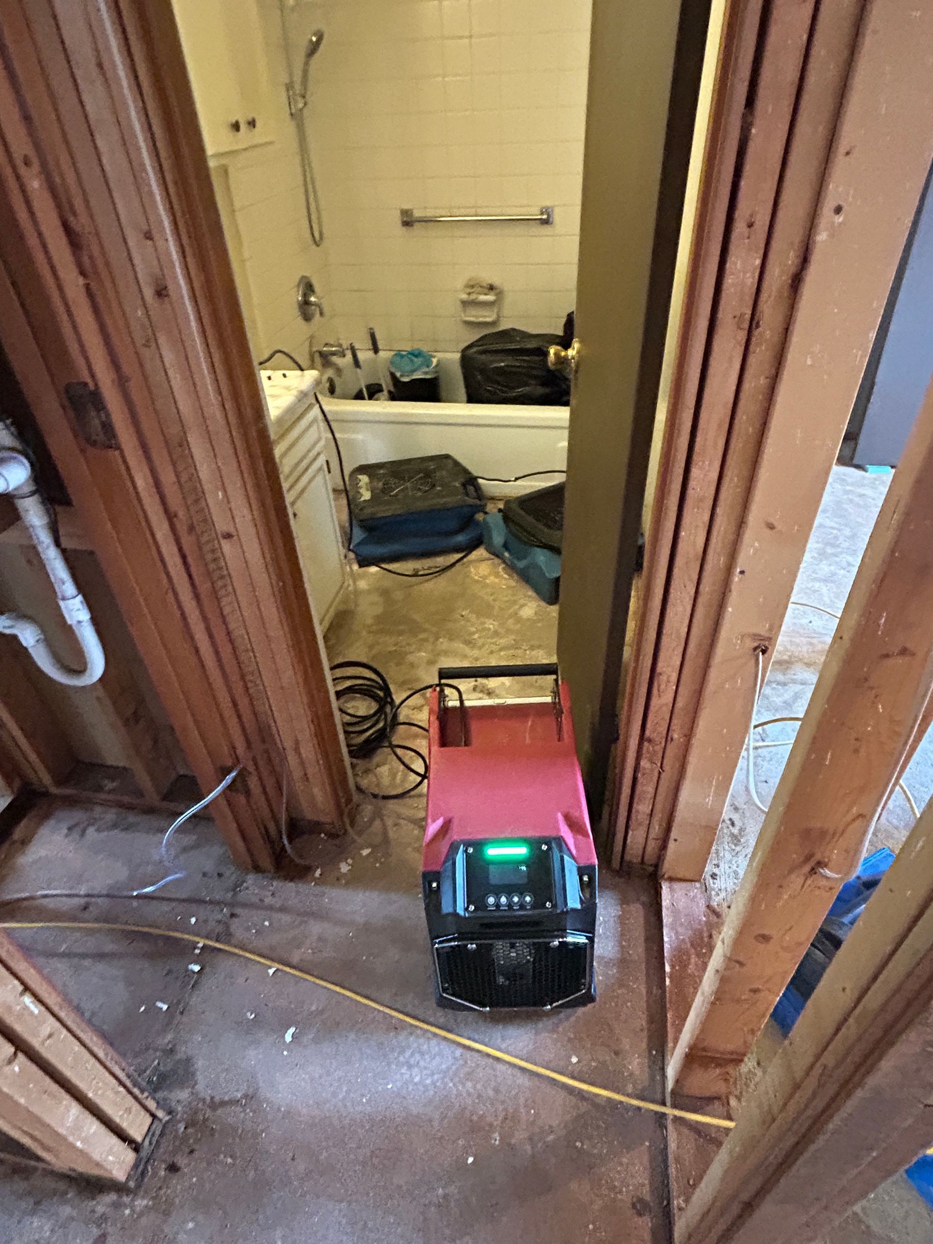 A red vacuum cleaner is sitting in a bathroom next to a bathtub.