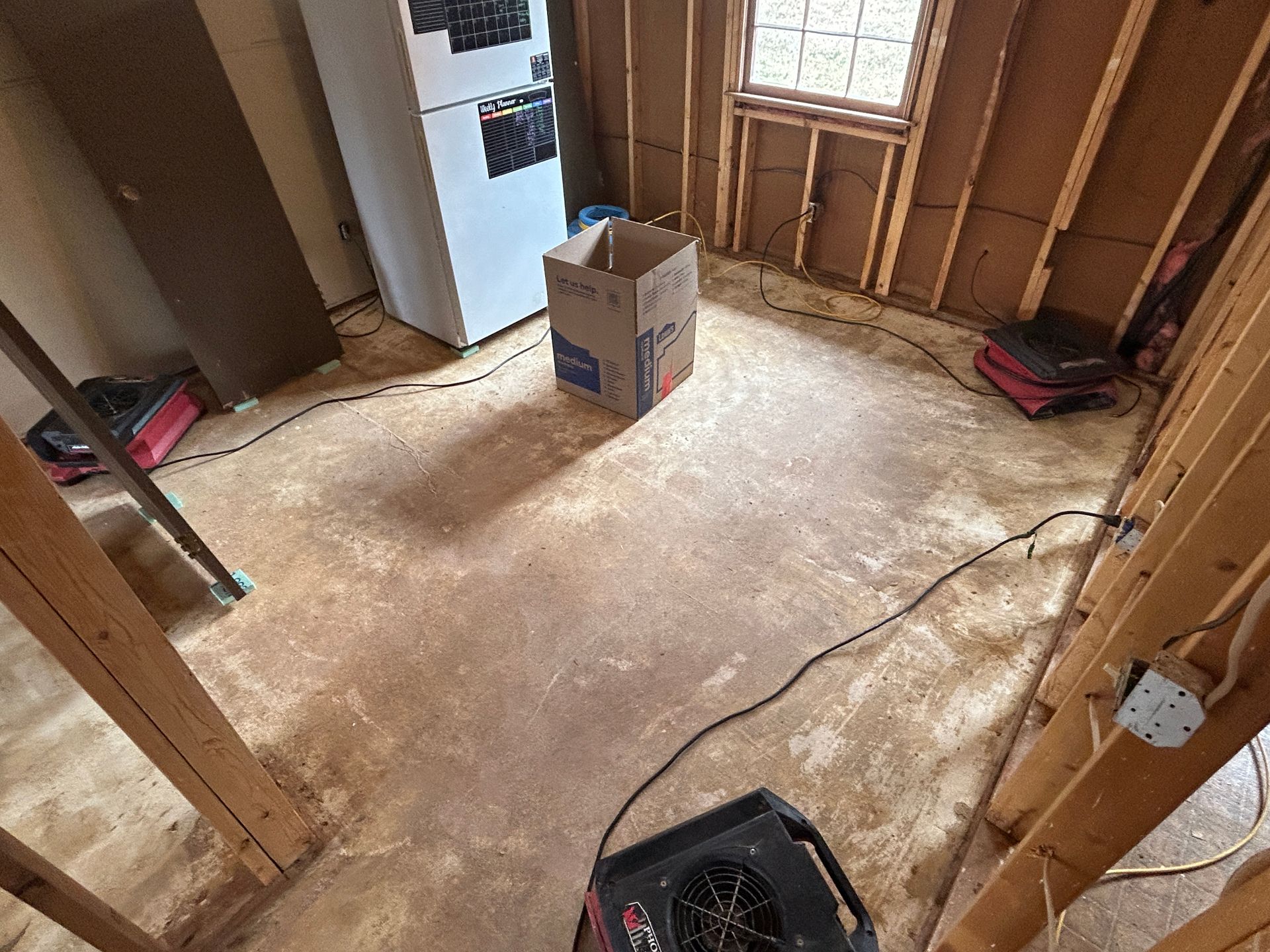 A cardboard box is sitting on the floor of a room under construction.