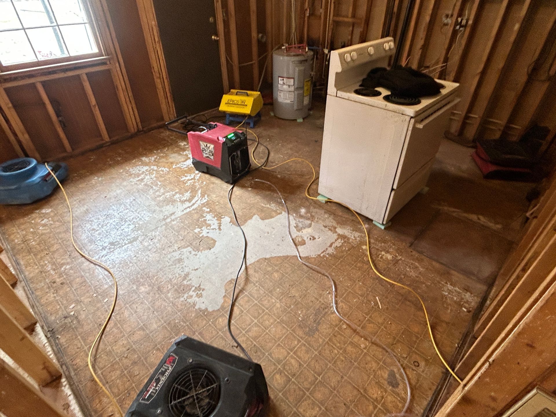 A room with a stove and a fan on the floor.
