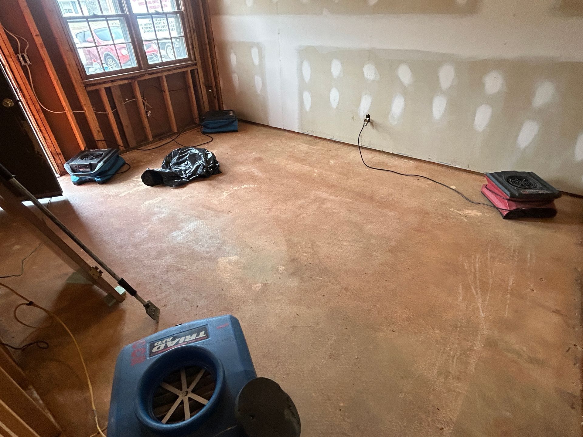 A room with a dryer on the floor and a bag on the floor.