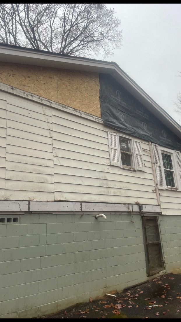 A white house with a black tarp on the side of it.