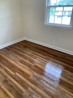 An empty room with hardwood floors and a window.