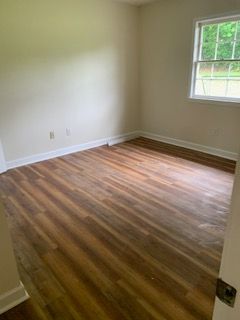An empty room with hardwood floors and a window.
