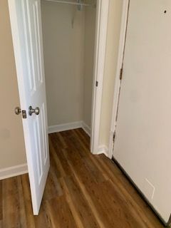 A closet with hardwood floors and a white door.