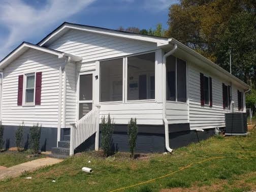 A white mobile home with a screened in porch and stairs.