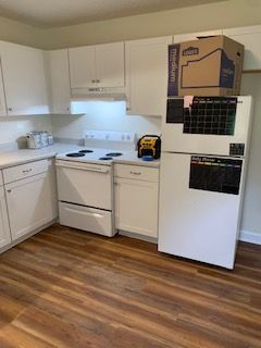 A kitchen with a refrigerator , stove , dishwasher and a box on the refrigerator door.