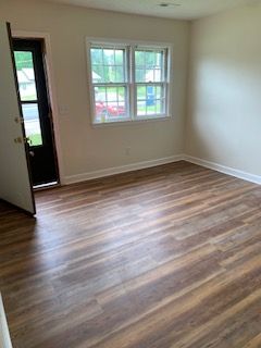 An empty room with hardwood floors and a window.