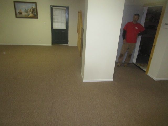A man in a red shirt is standing in an empty room