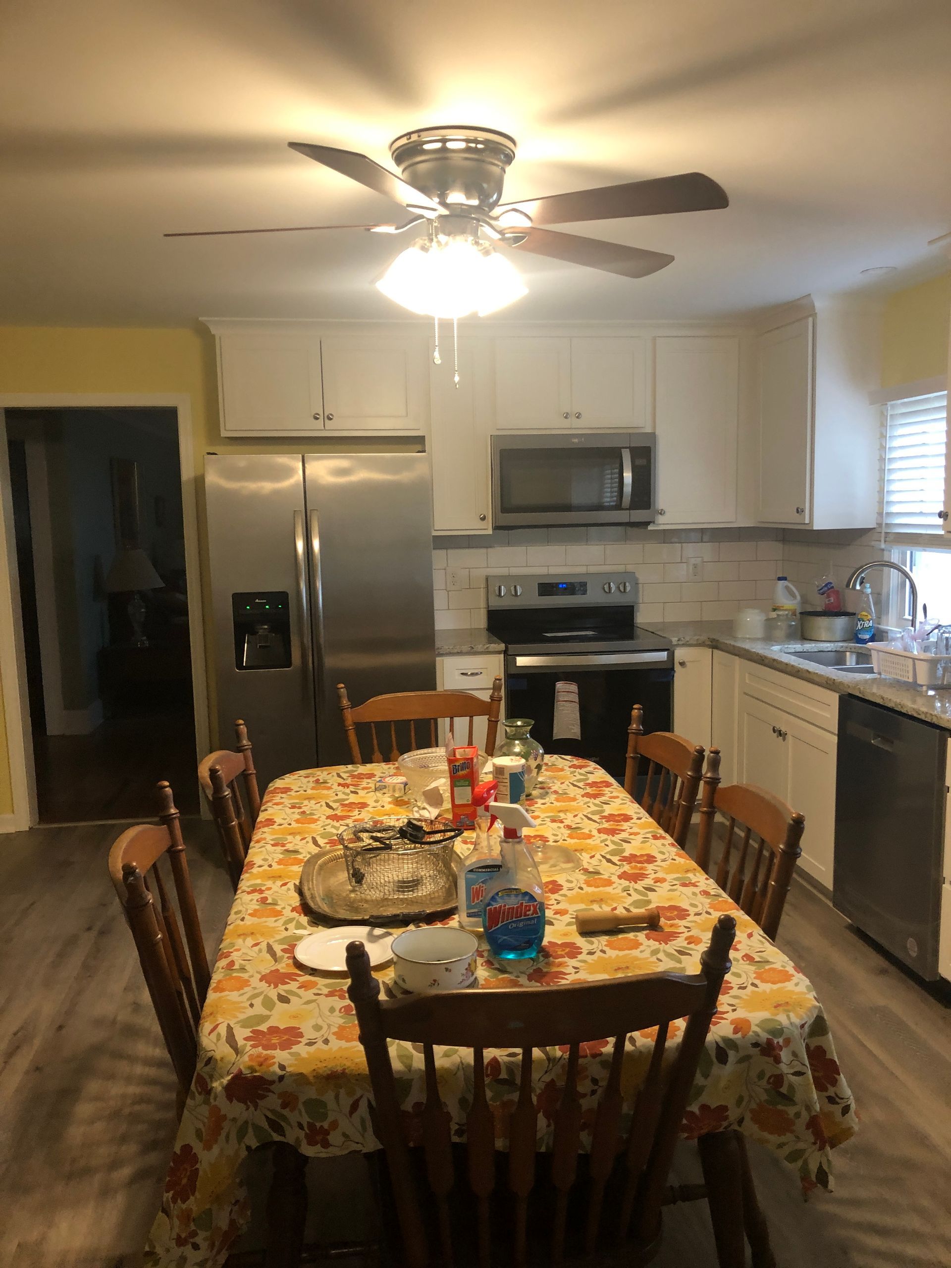 A kitchen with a table and chairs and a ceiling fan.
