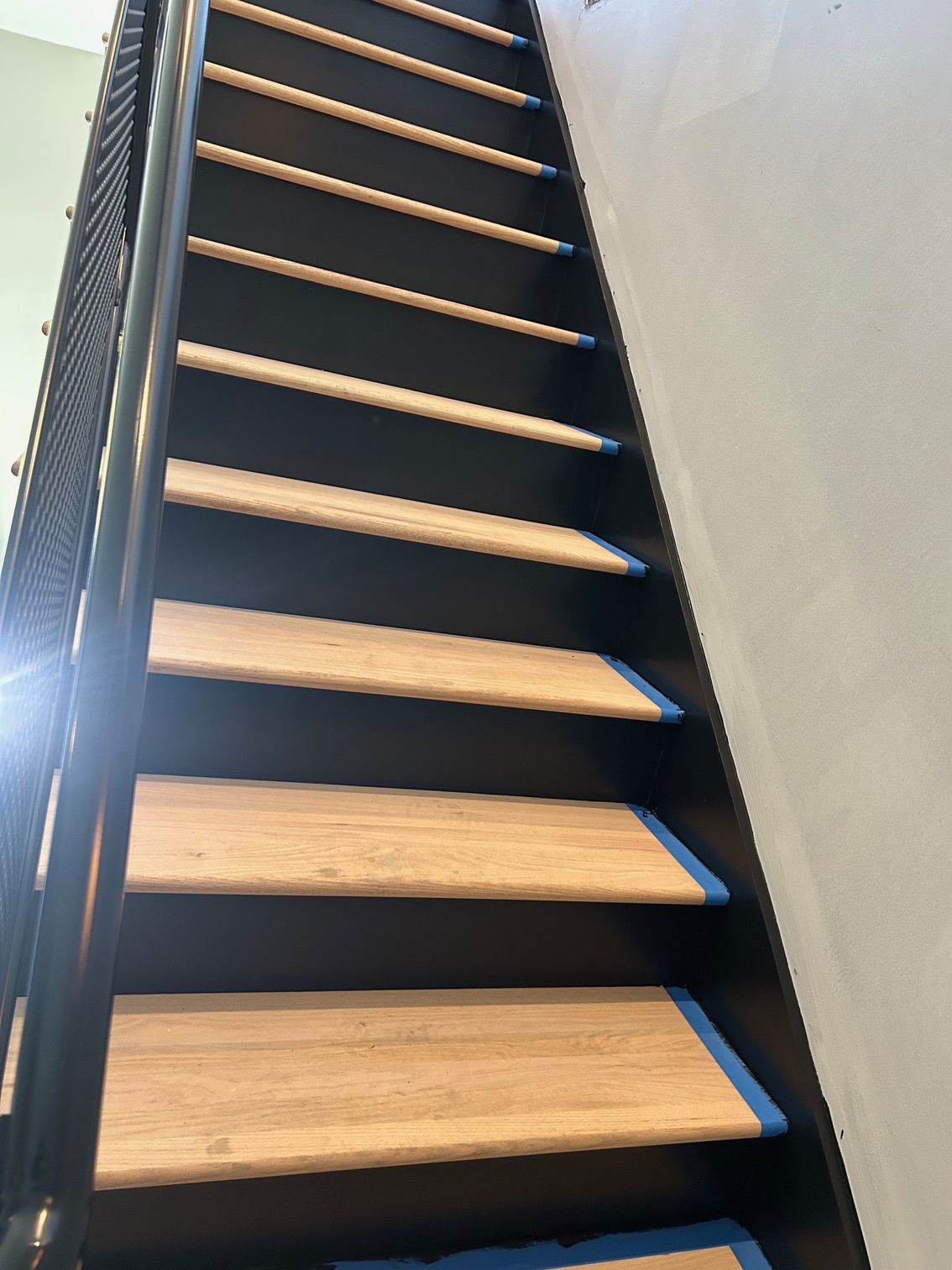 A staircase with wooden steps and a black railing