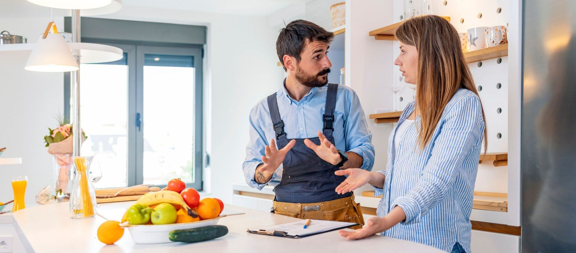 A man and a woman are standing in a kitchen talking to each other. - Home Reimagined