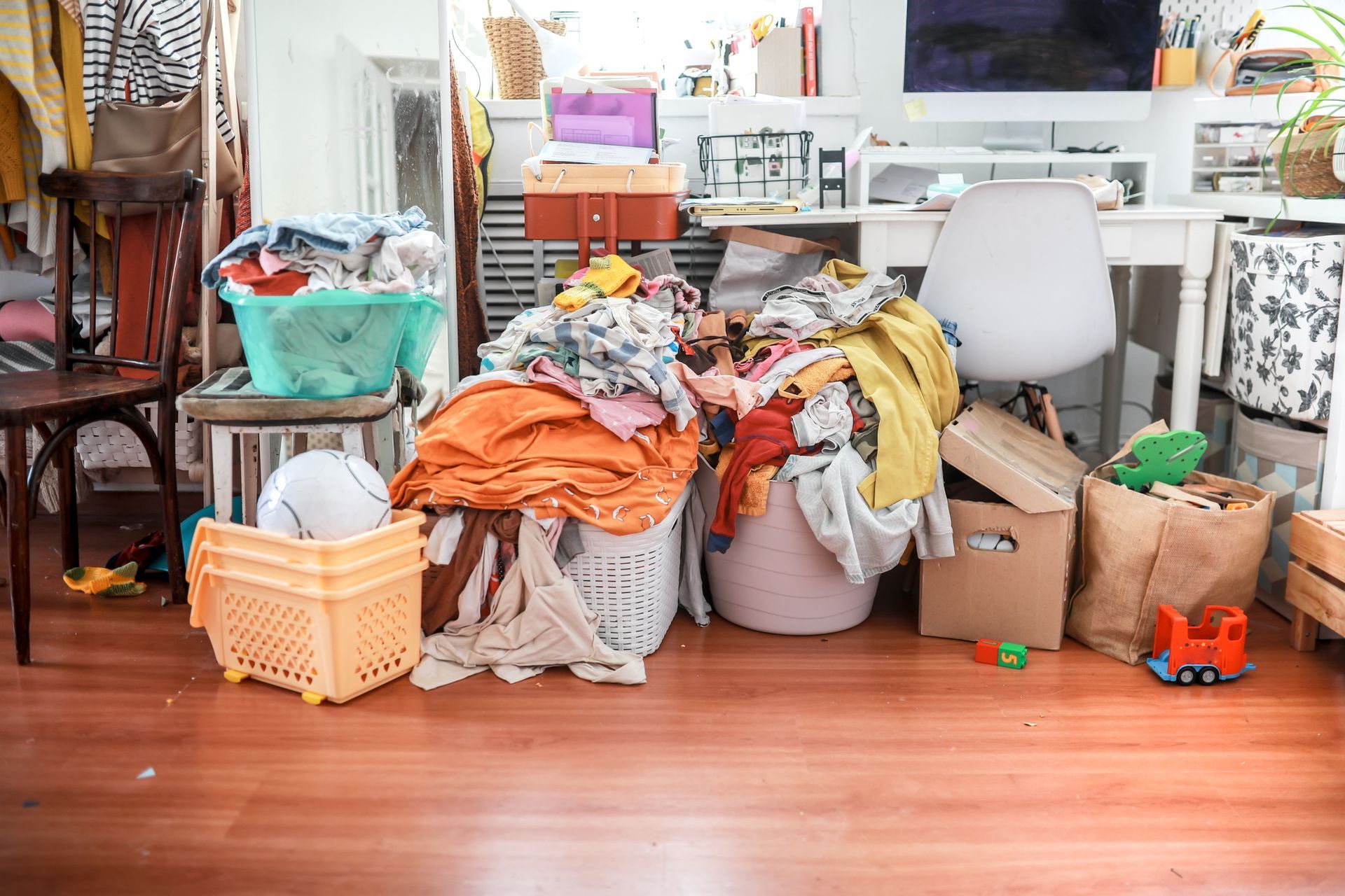 A messy room with a guitar and clothes on the floor.