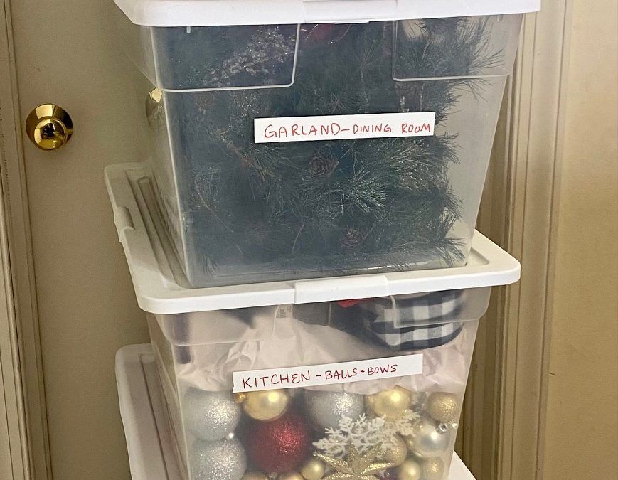 A stack of clear plastic bins filled with christmas decorations and a christmas tree. A stack of clear plastic bins filled with christmas decorations and a christmas tree.