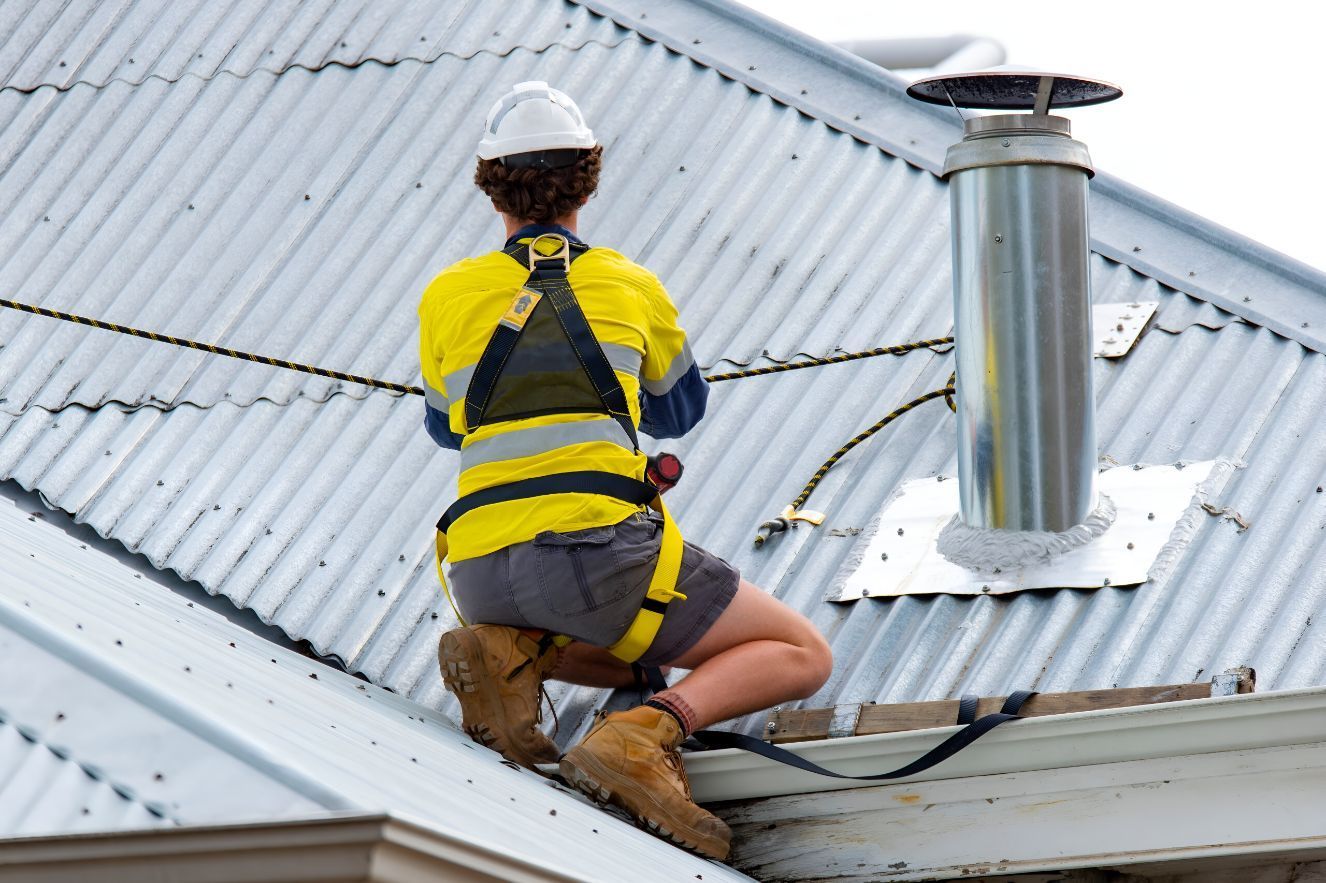 A Man is Sitting on the Roof of a Building — Goonellabah Roof Tilers In Alstonville, NSW