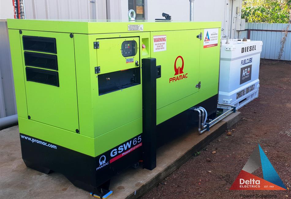 a green and black generator is parked next to a white building .
