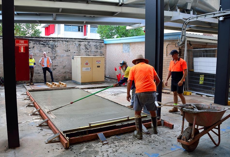 a group of construction workers are working on a concrete floor .