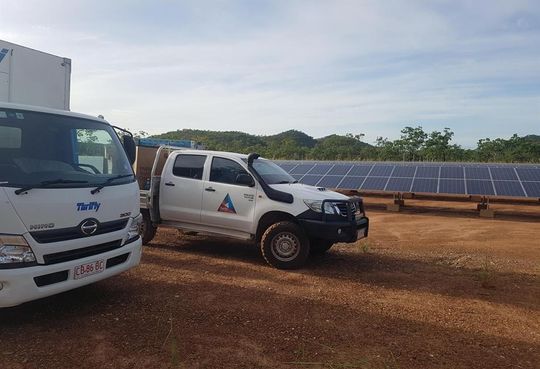 two trucks are parked next to each other in front of a solar panel .