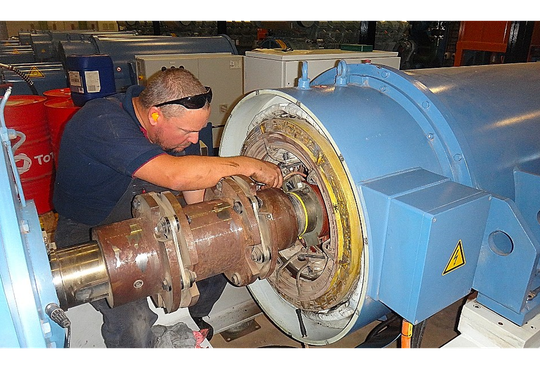 a man wearing safety glasses is working on a large machine