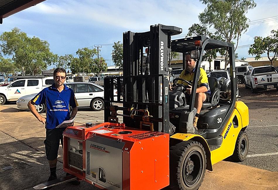 two men are standing next to a forklift in a parking lot .