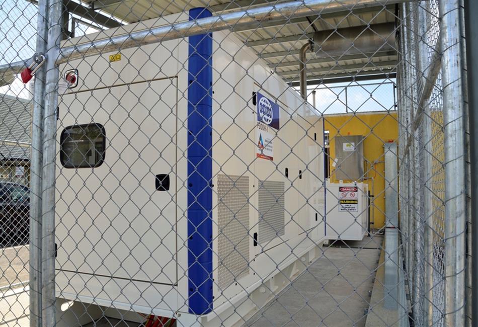a white and blue generator is behind a chain link fence