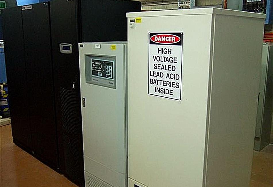a white cabinet with a danger sign on it that says high voltage sealed lead acid batteries inside