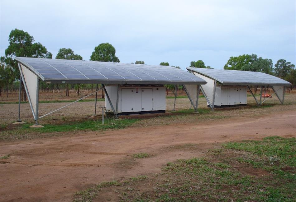 a row of solar panels sitting on top of a dirt field