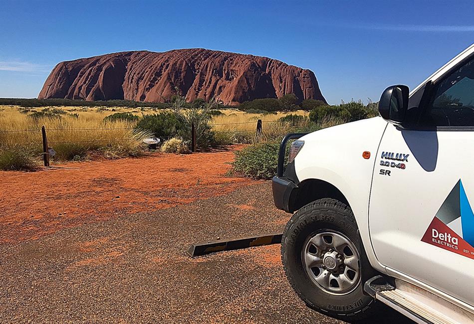 a white truck is parked in front of a large rock formation .