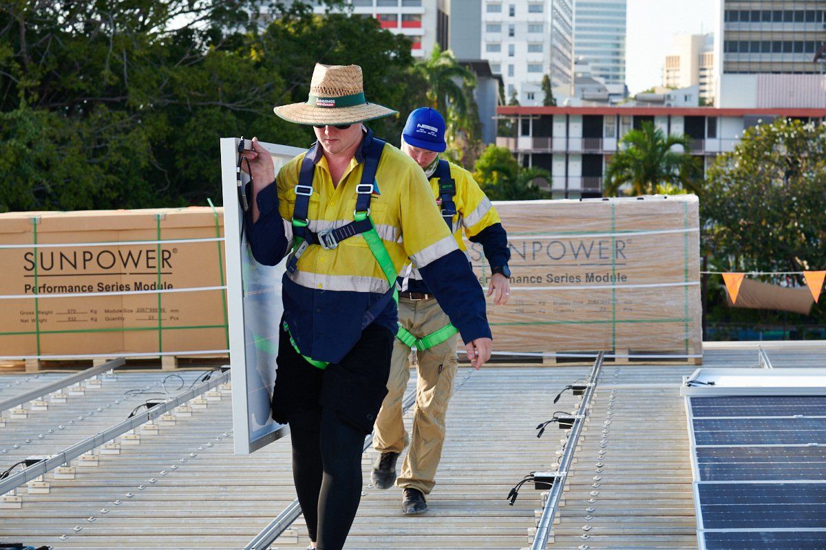 a man is carrying a solar panel while another man walks behind him .