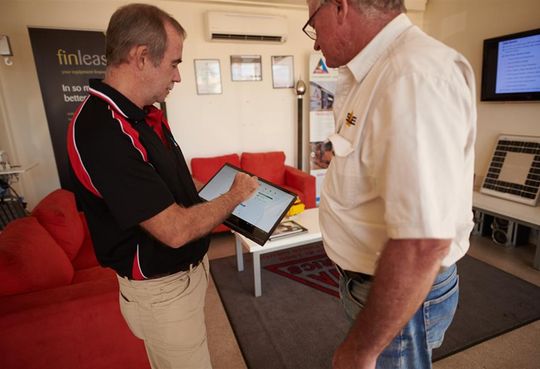 two men are looking at a tablet in a living room