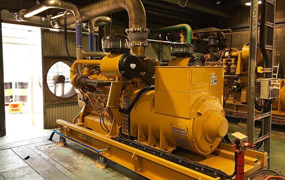 a large yellow generator is sitting in a room in a factory .