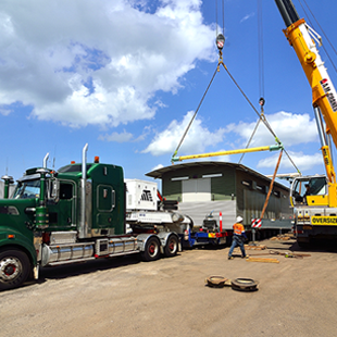 a yellow crane is lifting a green semi truck