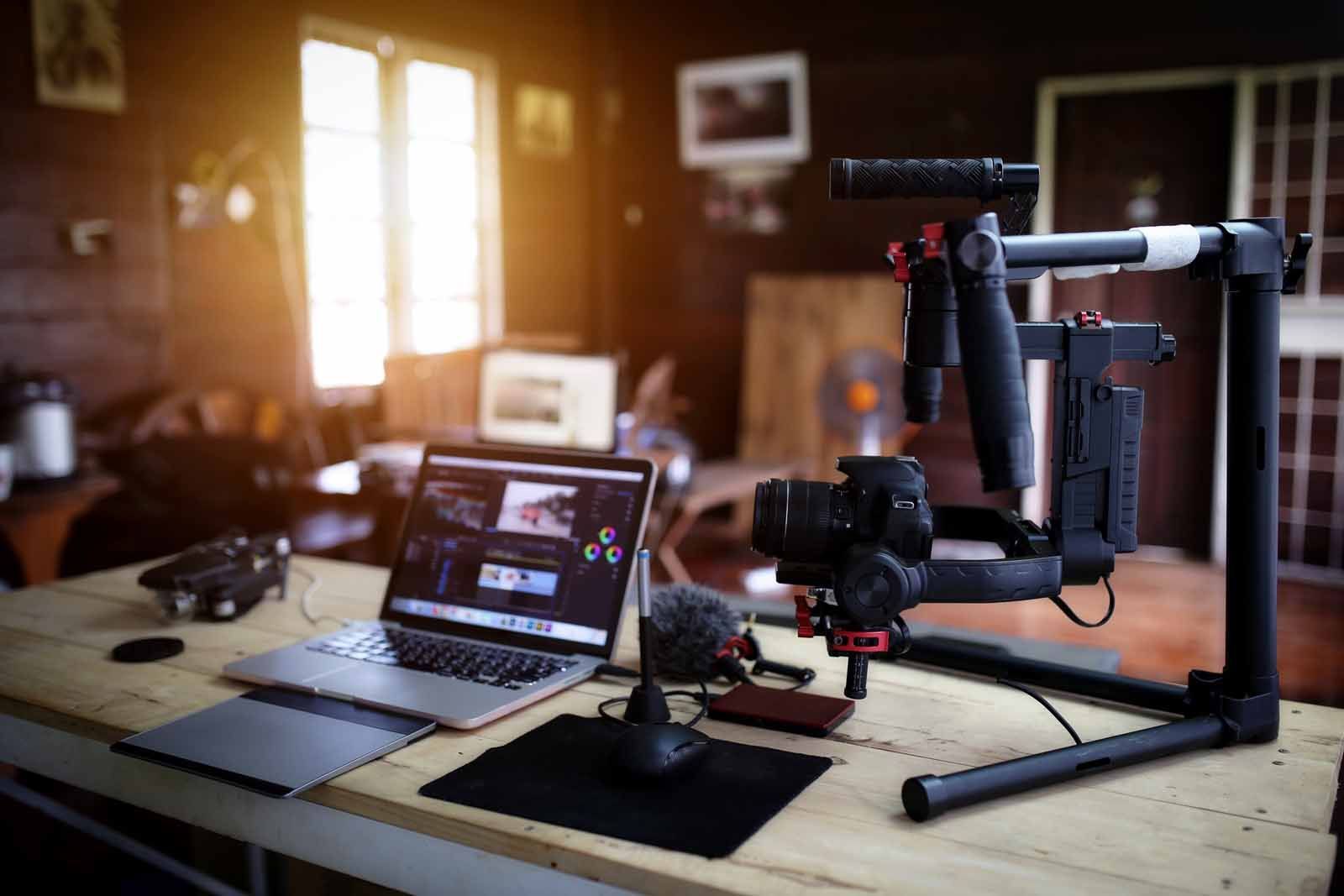 A camera is sitting on top of a wooden table next to a laptop.