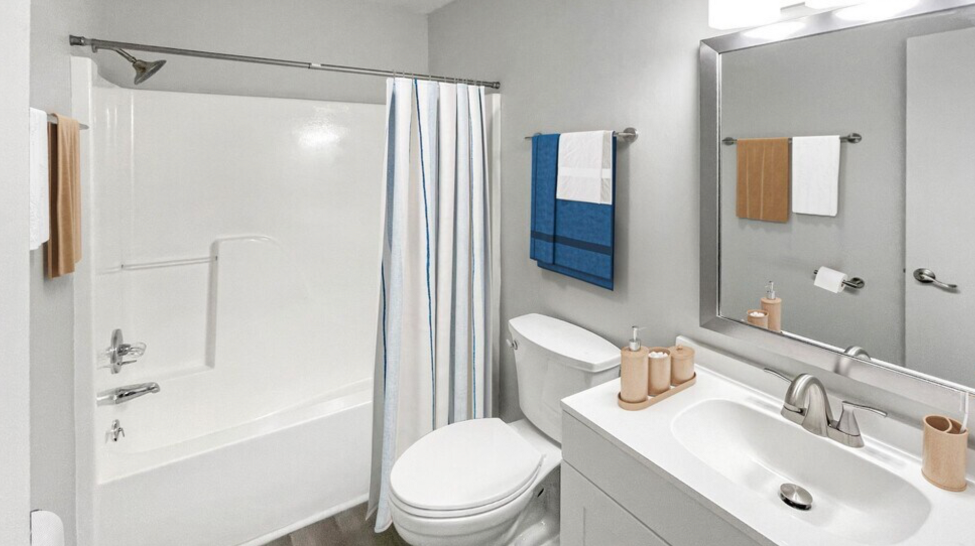 A bathroom with a toilet , sink , bathtub and mirror.