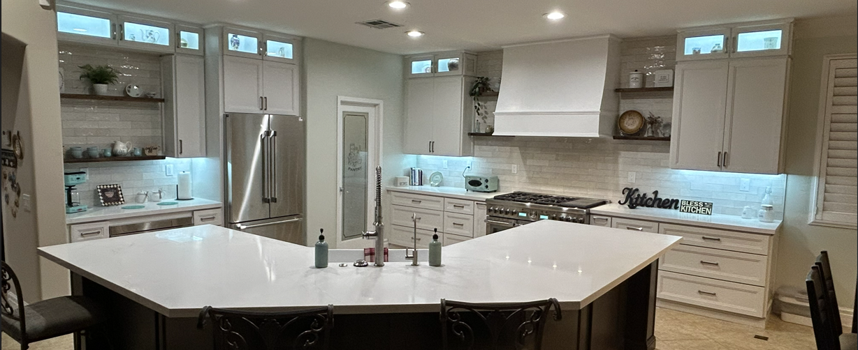 Modern kitchen with white cabinets, stainless steel appliances, and a large island.