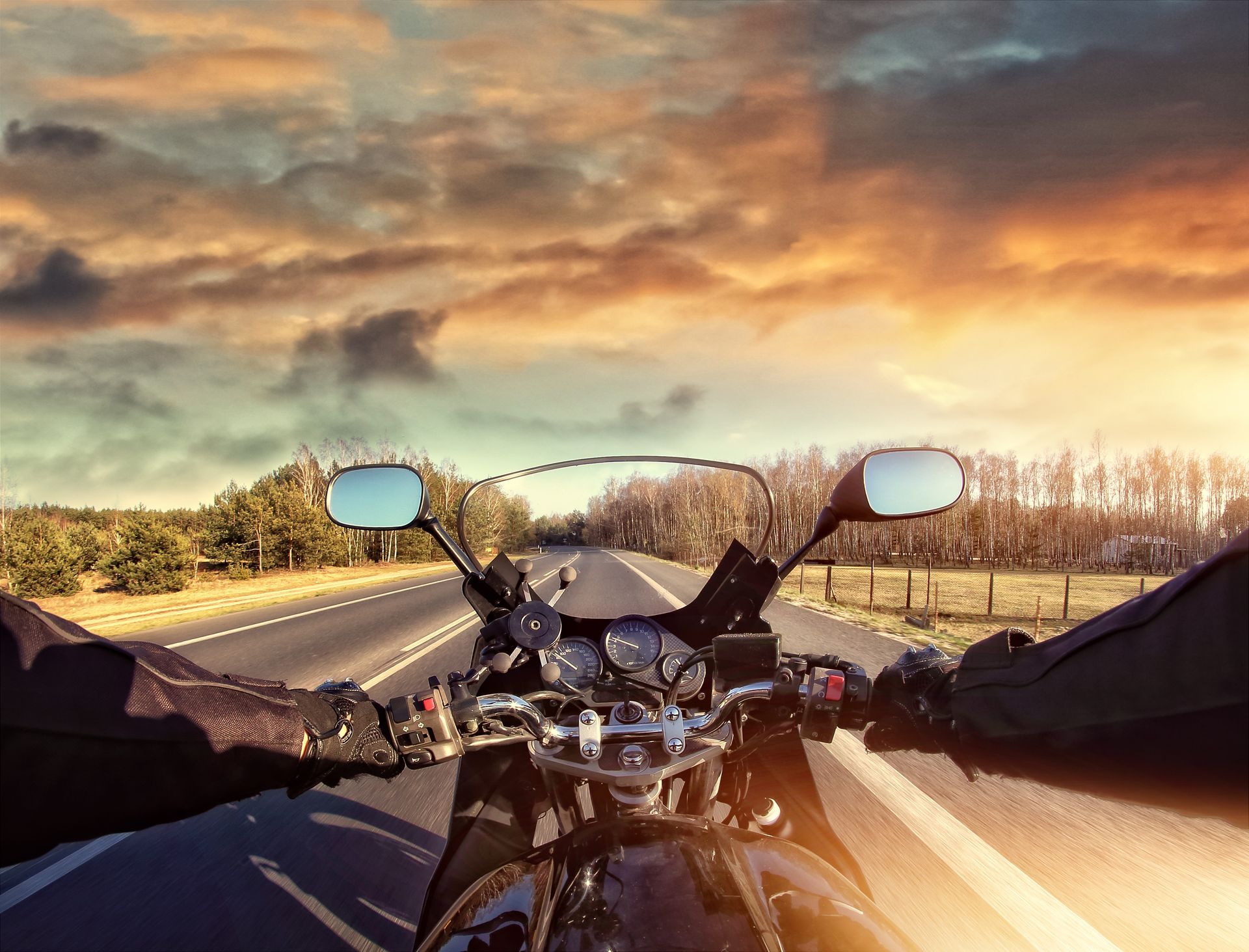 A person is riding a motorcycle down a highway at sunset.